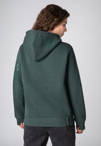 Donkergroene hoodie met een ruime capuchon, ribgebreide manchetten en zoom. Voorzien van bedrukte tekst op de achterkant en de linkerarm. Zachte, gestructureerde stof.