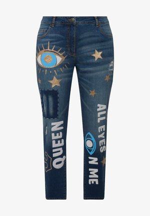 Des jeans en denim bleu foncé présentent des étoiles dorées pailletées et des graphiques en texte. Des patches usés et des motifs d'yeux ajoutent de l'intérêt visuel et de la texture.