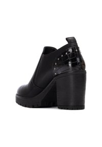 Botín de cuero negro de tacón alto con un acento negro texturizado y brillante de patrón de cocodrilo y detalles de tachuelas metálicas en el lateral.