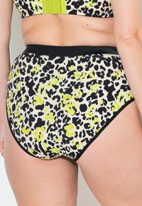 Bikini z wysokim stanem w wzór panterki z neonowozielonymi akcentami na jasnym tle, wykonany z elastycznego, miękkiego materiału.