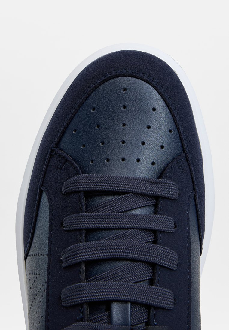 Sneaker blu navy con upper in pelle e camoscio, punta perforata, chiusura con lacci piani e suola in gomma bianca. Design con punta rotonda.