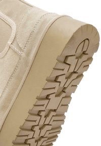 Stivale in suede beige con una suola in gomma spessa e testurizzata, caratterizzata da un motivo a zigzag. Dettaglio di cuciture laterali per una maggiore struttura.