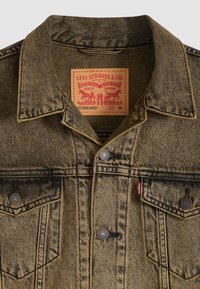 Τζιν μπουφάν σε ξεθωριασμένο κίτρινο-καφέ με μυτερό γιακά, εμπρόσθια κουμπιά με κούμπωμα, δύο τσέπες στο στήθος και ετικέτα με το λογότυπο στο εσωτερικό. Μέγεθος M.