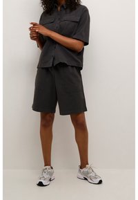 Kortærmet, mørkegrå skjorte med to brystlommer, kombineret med matchende shorts og lysegrå sportssko med sorte detaljer.