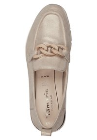 Chausson beige à enfiler avec une finition métallique, présentant une chaîne décorative dorée sur le coup de pied et une semelle contrastante noire. Texture douce dans l'ensemble.
