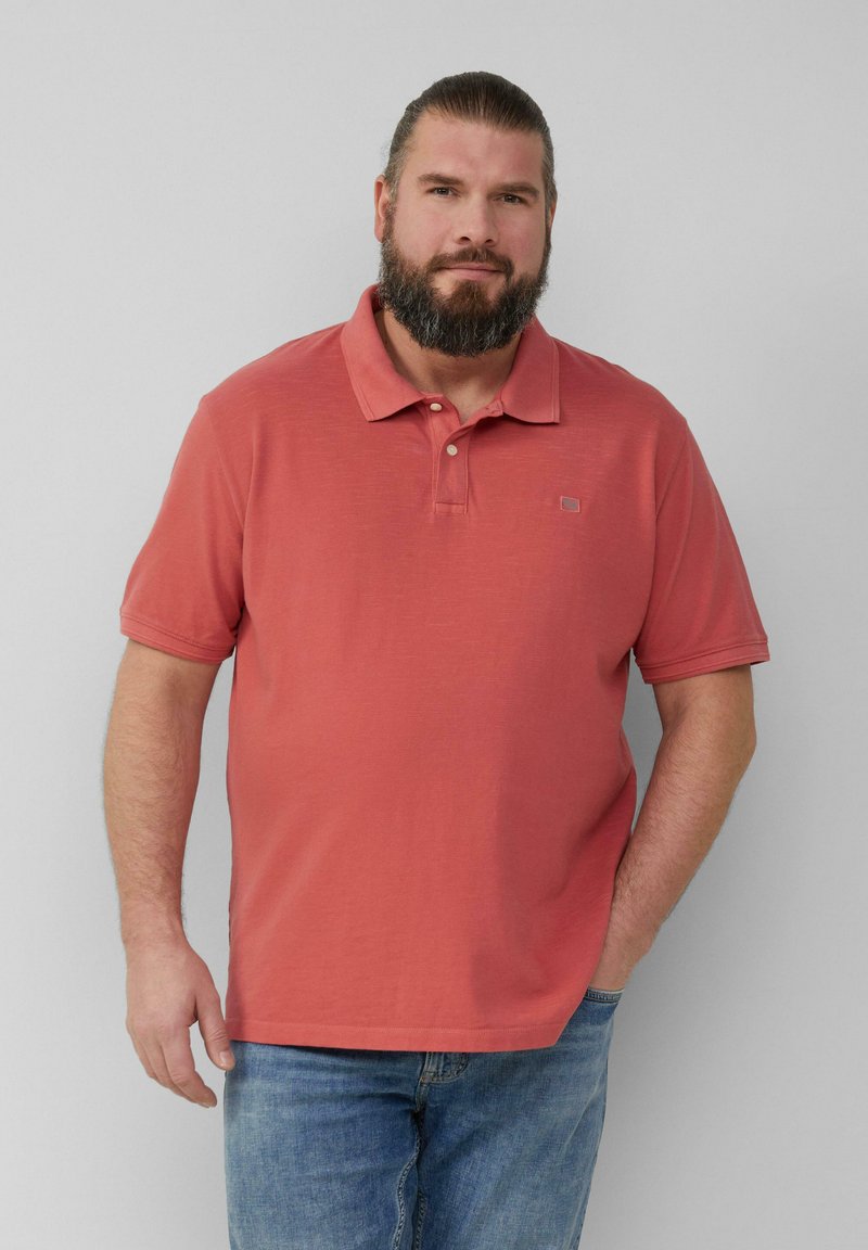 Koralowa koszulka polo wykonana z bawełny, z kołnierzykiem, trzema guzikami i krótkimi rękawami. Teksturowany materiał ma subtelny wzór.