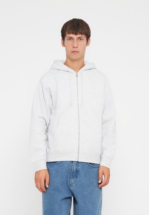 Light gray zip-up hoodie made of soft cotton blend, featuring a front pocket, drawstring hood, and ribbed cuffs, paired with blue denim trousers.