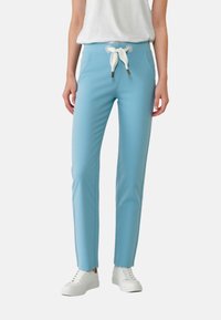 Light blue pants made of stretchy fabric, featuring a white drawstring waist, slim fit, and side accent seams, paired with white sneakers.