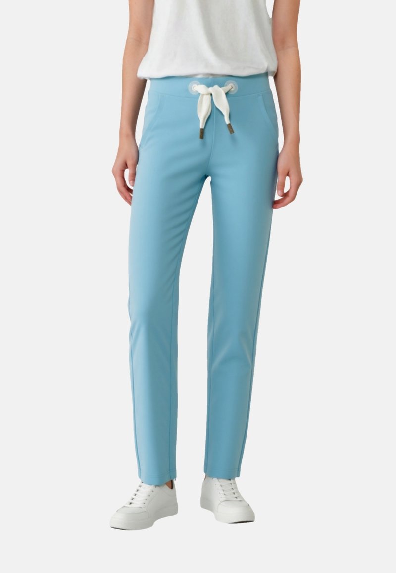 Light blue pants made of stretchy fabric, featuring a white drawstring waist, slim fit, and side accent seams, paired with white sneakers.
