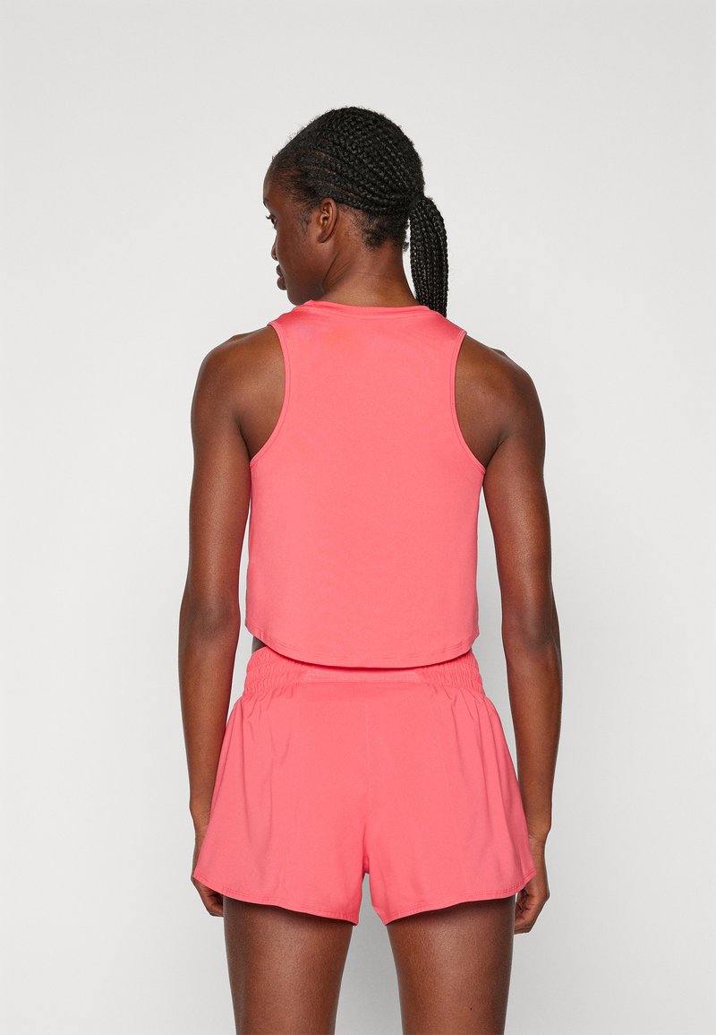 Top deportivo rosa sin mangas y pantalones cortos, con un diseño ajustado, textura suave y cinturilla elástica, detalles de costura visibles.