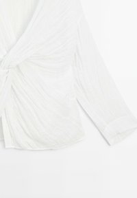Witte, gestructureerde blouse met een gedraaide voorzijde en lange mouwen. Heeft een gladde kraag en manchetten. De stof lijkt licht en luchtig.