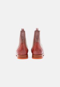 Ζευγάρι ανοιχτό καφέ δερμάτινων μποτών αστραγάλου με διακοσμητικές λεπτομέρειες brogue και θηλιές για pulling, απεικονιζόμενα από πίσω πάνω σε λευκό φόντο.