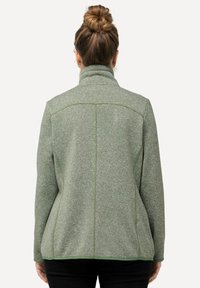 Grön fleecejacka med hög krage, texturerat mönster och kontrasterande sömmar. Har en skräddarsydd passform och långa ärmar.