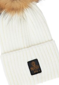 Berretto a coste bianco con pompon in pelliccia sintetica marrone e una patch nera con un'illustrazione di un cane e il testo "RexigiWear."