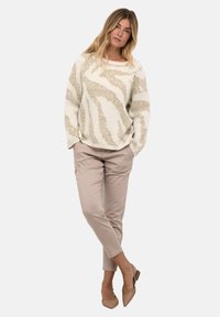 Maglione crema con motivo astratto beige, vestibilità rilassata, colletto rotondo, abbinato a pantaloni beige chiaro e ballerine a punta.