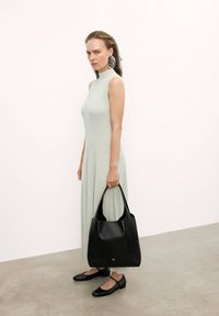 Jasnozielona, prążkowana sukienka bez rękawów, plisowana spódnica, czarna skórzana torba na ramię z regulowanymi uchwytami oraz czarne baleriny z paskiem na kostce.