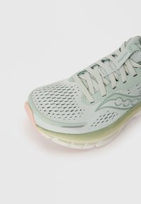 Baskets de sport vert clair en mesh et matériaux synthétiques. Présentent un dessus texturé, un laçage et une semelle rembourrée multicolore.