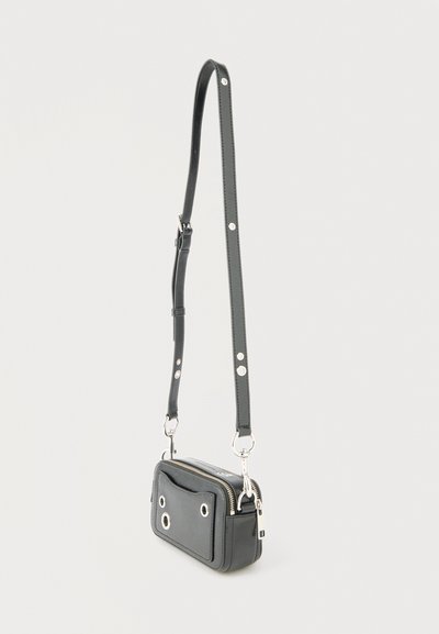 Μικρή μαύρη δερμάτινη τσάντα χιαστί με ασημένιο φερμουάρ και διακοσμητικές ασημένιες τρύπες, με ρυθμιζόμενο λουράκι με ασημένια καρφιά.