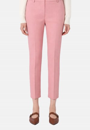 Pantaloni rosa slim fit e cropped indossati con un maglione color crema e scarpe Mary Jane marroni con punta e fibbie.