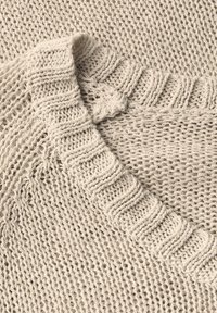 Strickpullover in hellbeige mit lockerer Maschenstruktur, ausgestattet mit einem gerippten Saum am Ausschnitt und einem strukturierten, offenen Muster über das gesamte Kleidungsstück.