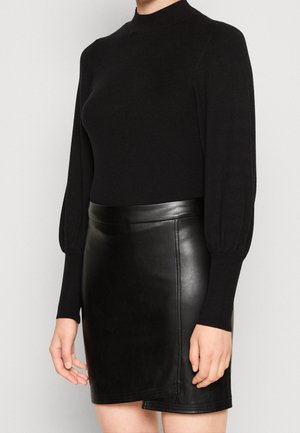 Maglione nero a coste con maniche lunghe e puffate abbinato a una gonna mini nera in pelle aderente, che mette in evidenza una superficie liscia e linee pulite.