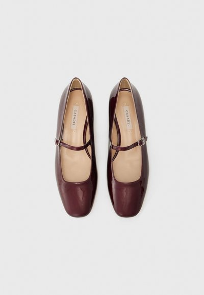 Bailarinas em couro patente bordeaux com biqueira quadrada e uma única alça ajustável. Textura suave, design minimalista, palmilhas com marca.