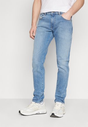Lys blå denimjeans med slim fit, som har fem lommer og subtile slitasjer på lårene. Sammen med hvite joggesko.