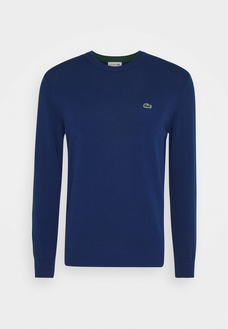 Pull à manches longues bleu marine avec col rond et petit logo crocodile vert sur le côté gauche de la poitrine.