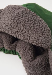 Green fabric with soft, gray fleece lining, featuring a plush texture and gathered edge. Smooth, contrasting materials create a layered look.