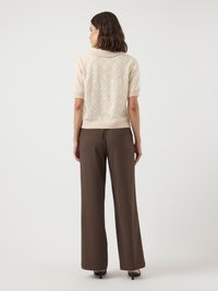 Μπεζ πουλόβερ με κοντά μανίκια, υφασμένη κεντητική, ριμπ τελείωμα και κλασικό γιακά· συνδυασμένο με καφέ παντελόνια με φαρδύ πόδι και εφαρμοστή γραμμή.