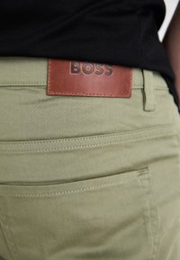 Svijetlozelene, prilagođene hlače od mješavine pamuka, s smešnim kožnim alludetom na pojasu s ugraviranim "BOSS" i stražnjim džepovima.