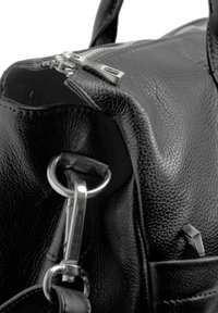 Black leather handbag featuring a textured surface, metallic zipper, and a loop attachment. Detailed stitching and angular accents visible.