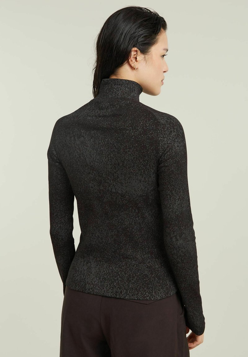 Czarna bluzka z długim rękawem i wysokim kołnierzem, z wyraźnym wzorem. Materiał wydaje się elastyczny i dopasowany, zaprojektowany z myślą o komforcie.