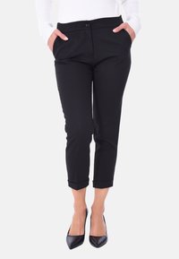 Pantaloni neri sartoriali con vita media, due tasche frontali, orli con risvolto e un piccolo dettaglio con bottone anteriore. Tessuto dalla texture liscia.