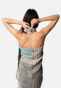 Sciarpa in cotone tessuta con una combinazione di motivi geometrici in teal, grigio e arancione, con bordi frangiati e un aspetto texture.