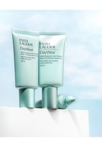 Zwei hellblaue Tuben der Estée Lauder DayWear Feuchtigkeitscreme mit einer glatten Textur und einem Drehverschluss, die auf einer weißen Oberfläche liegen. Mit der Kennzeichnung SPF 15.