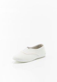 Zapato de lona blanco sin cordones con una textura suave, punta redonda y costuras tonales. El interior presenta rayas alternas en gris y blanco.