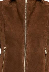 Bruine suède jas met een centrale metalen rits en twee zijzakken met rits, met een gladde textuur en een getailleerd ontwerp.