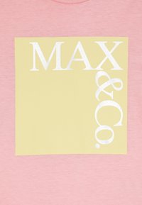Rausvas audinys turi didelį geltoną kvadratą su balta užrašu "MAX & Co." įkomponuotu įstrižai ir šiek tiek italizuotu.
