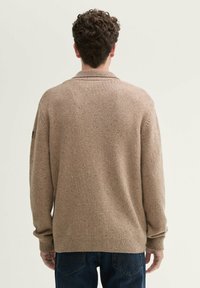 Strickpullover in hellbeige mit strukturiertem Finish, geripptem Kragen und Bündchen. Mit leichten Sprenkeln und einem lässigen Schnitt.