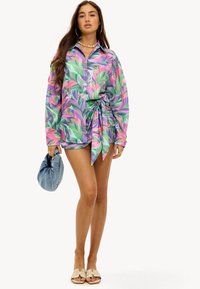 Kleurvol overhemd met een bladpatroon, gemaakt van lichtgewicht stof. Gecombineerd met shorts en een denim pouch tas. Lichte sandalen.