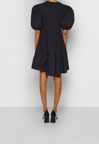 Black puff-sleeve dress with a tiered design, made of lightweight fabric, featuring a round neckline and a relaxed silhouette.