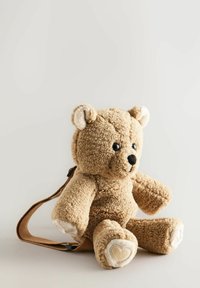Zachte, tan kleurige pluche teddybeer met crèmekleurige accenten, grote zwarte ogen en een bruine riem. Getextureerde, fluffy stof en hartvormige pootdetails.