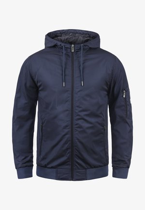 Veste bleu marine en nylon lisse, avec fermeture éclair à l'avant, capuche avec cordon de serrage et poignets côtelés. Comprend des poches zippées sur les côtés et la poitrine.