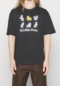 T-shirt noir en coton avec des graphismes colorés de My Little Pony. Coupe décontractée avec un col rond et des manches courtes.