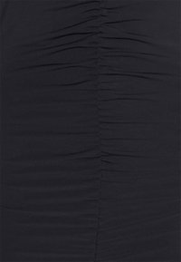 Mustat mekko, joka on valmistettu pehmeästä ja joustavasta kankaasta, jossa on pystysuora rypytys yksityiskohta, joka lisää tekstuuria ja visuaalista mielenkiintoa pinnalle.