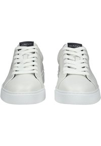 Sneaker bianche in pelle con superficie liscia, punta rotonda e suola in gomma bianca. I lacci sono bianchi con un'etichetta logo nera sulla linguetta.