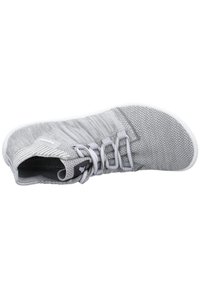 Mesh athletic shoe in light grey with white sole, featuring a smooth, textured upper, and lace-up design with subtle branding detail.