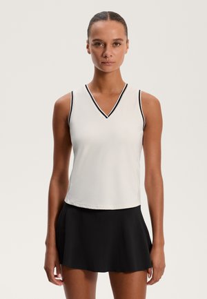 Fehér, ujjatlan felső V-nyakkal és fekete díszítéssel, fekete harangszoknyával párosítva. Simavászon anyag, laza dizájn, letisztult vonalak.