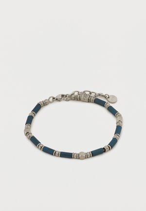 Ασημένιο και σκούρο μπλε βραχιόλι με χάντρες, με κούμπωμα αστακού και μικρή στρογγυλή ετικέτα μάρκας σε λευκό φόντο.